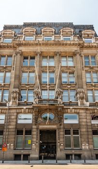 Antwerpen, Belgium - June 23, 2019: Beige-brown facade of monumental Diamond Exchange building with flag poles and silver sky In Pelikaanstraat.