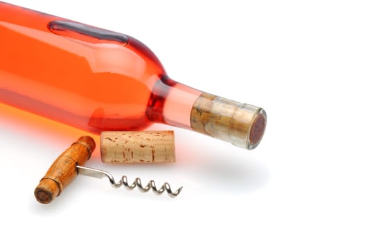 Closeup of a blush wine bottle and corkscrew laying on a white background with reflection and shadow. 