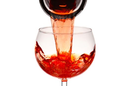 Closeup of a wineglass with red wine pouring from a carafe.