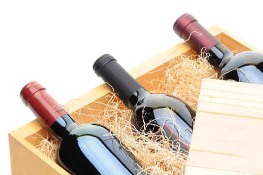 Closeup of three Cabernet Sauvignon wine bottles on their side in a wooden crate. Crate lid is pulled partially back exposing the bottles and packing excelsior. Horizontal format isolated on white.