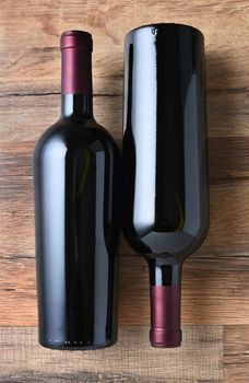 Top view of two red wine bottles on a rustic wood table. 