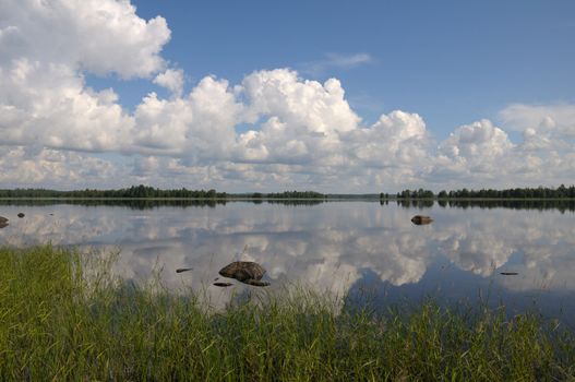 The beautiful picture of Karelian forest at the edge of a lake, and some huge boulder in this lake