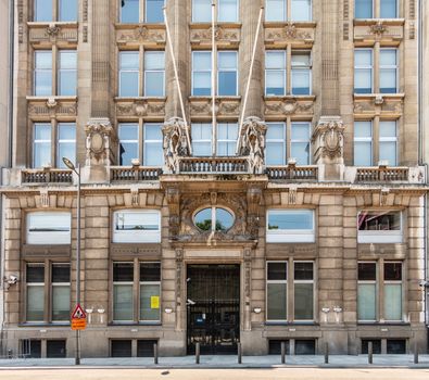 Antwerpen, Belgium - June 23, 2019: Entrance to Beige-brown facade of monumental Diamond Exchange building with flag poles In Pelikaanstraat.