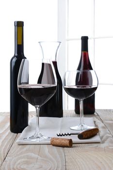 High key wine still life. Vertical format on a farmhouse style table with a white background with window panes. Shallow depth of field.