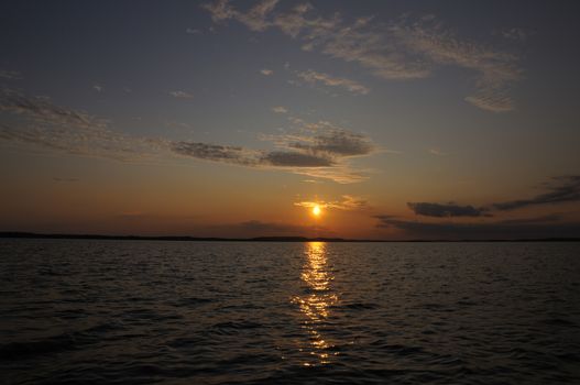 The final stage of a cloudy sunset above the huge lake in Karelia region. The picture is colorful and relaxing.