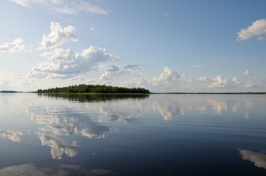 The beautiful picture of Karelian forest at the edge of a lake, and some huge boulder in this lake