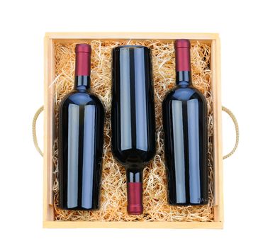 Closeup of three red wine bottles in a wooden case with packing straw. Overhead shot on a white background.