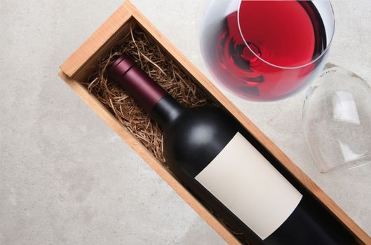Cabernet Sauvignon: A bottle in wood case with a glass of red wine and an empty glass on its side with copy space.