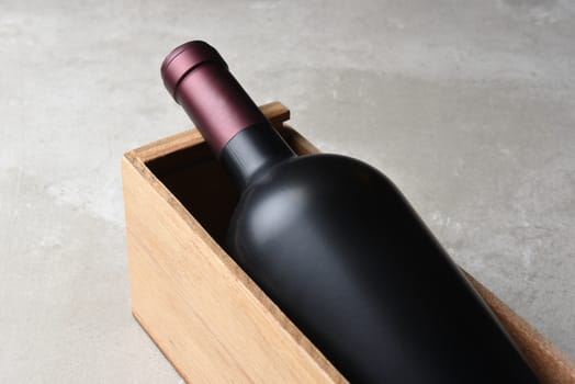 Wine Bottle Still Life: Closeup of a Wine Bottle in a Wood Box. No label on gray concrete table top