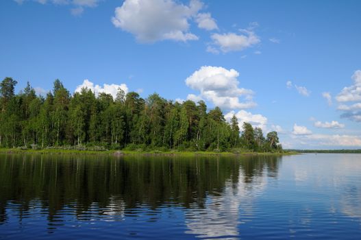 The beautiful picture of Karelian forest at the edge of a lake, and some huge boulder in this lake