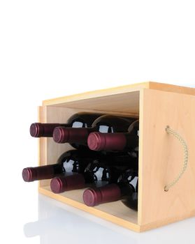 Closeup of six Cabernet Sauvignon wine bottles in a wooden crate laying on its side. Vertical format isolated on white with reflection.