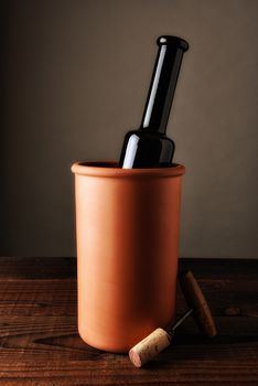 Port wine bpottle in a terra cotta chiller on a rustic wood table.