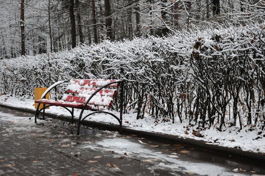 A bench in a winter park, covered by snow.