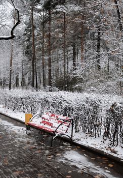 A bench in a winter park, covered by snow.