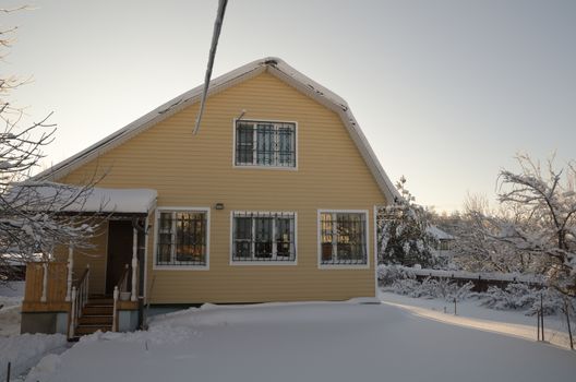 Beautiful winter view of the cottage and frozen trees under the blue sky