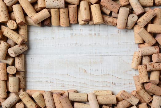 Overhead shot of a group of wine corks forming a frame on a rustic whitewashed wood table. Horizontal format. 