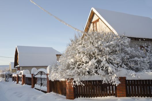 Beautiful winter view of the cottage and frozen trees under the blue sky