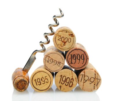 Closeup of a group of vintage dated wine corks and an antique corkscrew on white with reflection.