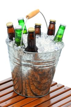 Beer Bucket filled with assorted bottles and ice cubes on teak table in front of a white background.