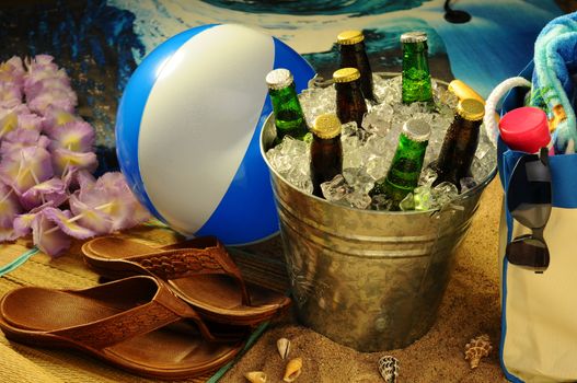 Beach still life with warm afternoon sunlight. Beach ball, tote, lotion, sandals, sunglasses and lei surround a bucket of assorted beer bottles on ice.