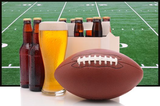 Six pack of beer and frothy glass with an American Football in front of a big screen television. Great for Super Bowl themed projects.
