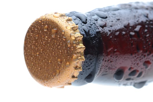 Closeup of a brown beer bottle cap and neck covered with condensation. Horizontal format over a white background. Bottle is at an angle focus on the bottle cap. Shallow Depth of Field.