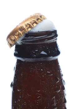 Closeup of a beer bottle top with the cap askew and foam bubbling up. Vertical format over a white background.