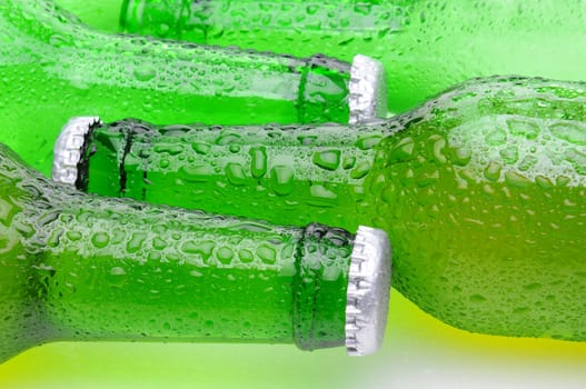 Closeup of green beer bottles laying on their side in horizontal format. Bottles are covered with condensation.