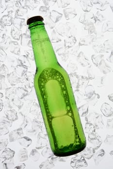 A single green bottle of beer backlit on a bed of ice. The bottle has no label. Vertical Format.