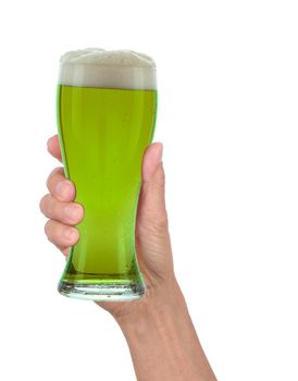 Man's hand holding up a glass of foamy green beer to celebrate St. Patrick's Day. Vertical format over a white background