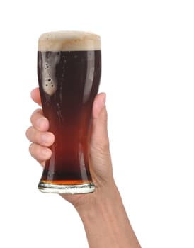 Closeup of a male hand holding up a glass of foamy dark ale over a white background. Vertical format with drip running down the side of the beer glass.
