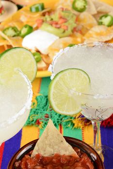 Cinco de Mayo Concept: Margaritas and Mexican food on a colorful  table cloth, with nachos and salsa.