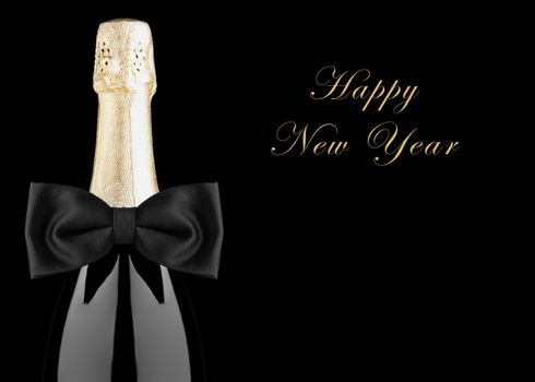 Closeup of a Champagne Bottle with Black Bow Tie isolated on black background with Happy New Year.