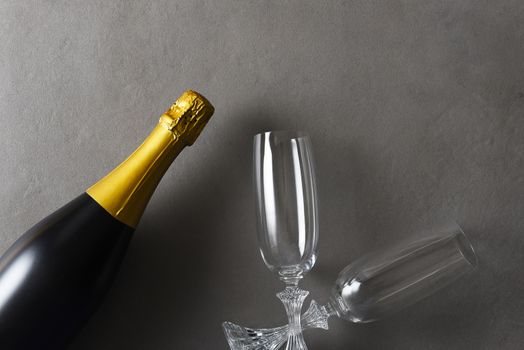 Flat lay Champagne and two glasses on a dark gray table with strong side light.