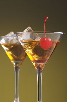 Two Manhattan Cocktails in Martini Glasses on warm background vertical format
