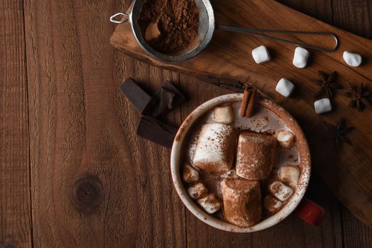 Overhead shot of a large mug of hot chocolate with marshmallows on a rustic wood kitchen table, with copy space.