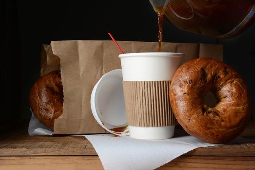 A disposable cup of coffee and bag of bagels. A to-go breakfast meal 