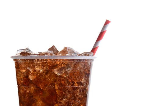 Closeup of a plastic cup filled with ice and cola. Only half the cup is shown with a red and white striped straw over a white background.