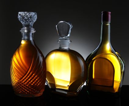 Three whiskey decanters against a light to dark gray background.