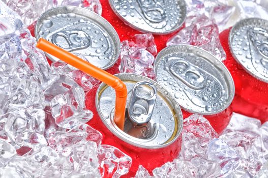 Soda Cans in Ice with a drinking straw with condensation.