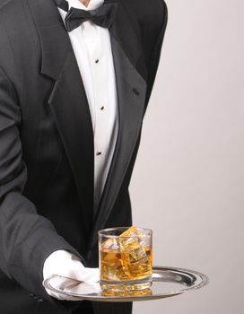 Waiter in tuxedo Presenting Cocktail on silver tray vertical format torso only