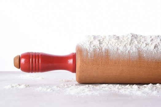 Closeup of a rolling pin with flour on the implement and the kitchen counter.