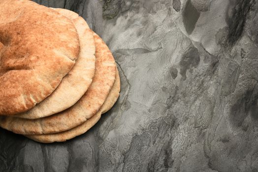 Pita bread loaves on dark gray slate with copy space.