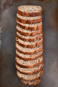 Top view of a sliced loaf of multi-grain bread on a baking sheet.