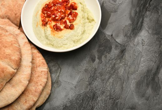 Pita bread and edamame hummus on a slate table with copy space.