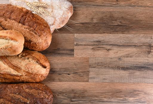 Five different loaves of bread on a wood table with copy space. Horizontal format.