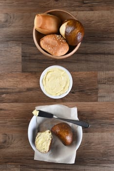 Bowl of assorted dinner rolls with butter crock and bread plate. Vertical format from a high angle.