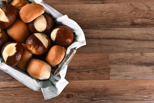 High angle shot of assorted dinner rolls in basket. On a rustic wood table with copy space.