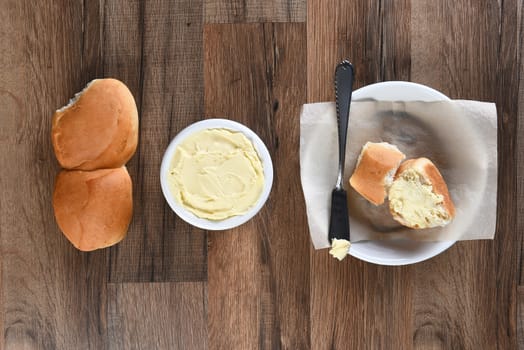 Overhead view of Dinner rolls Bread Plate and Butter Crock on a rustic wood table.