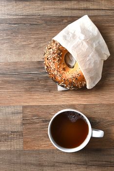 A bagel and a cup of coffee viewed from a high angle. Vertical format with copy space.
